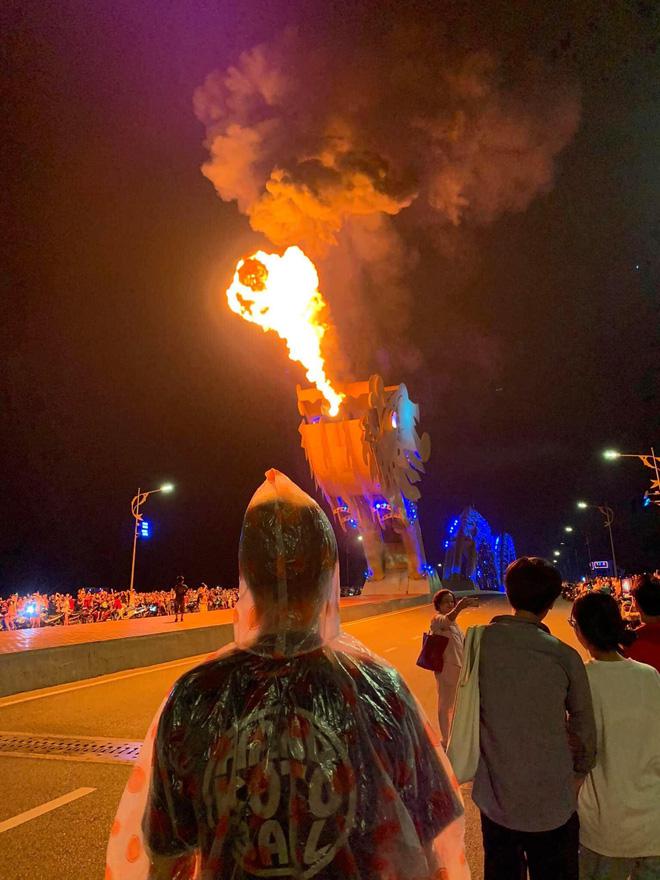 Nam thanh niên mặc áo mưa kín mít đi xem cầu Rồng phun lửa, phun nước khiến những người xung quanh tò mò. 