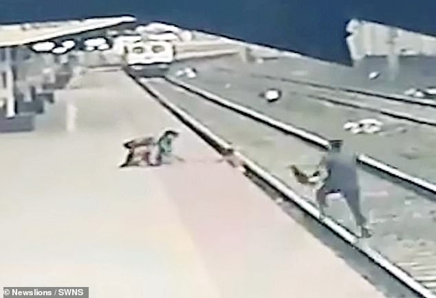 Nhân viên đường sắt chạy tới cứu em bé.