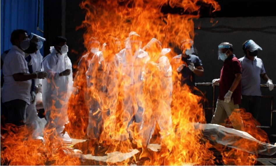Thân nhân mặc đồ bảo hộ khi một bệnh nhân COVID-19 được hỏa thiêu ở New Delhi ngày 21/4 Ảnh: Reuters