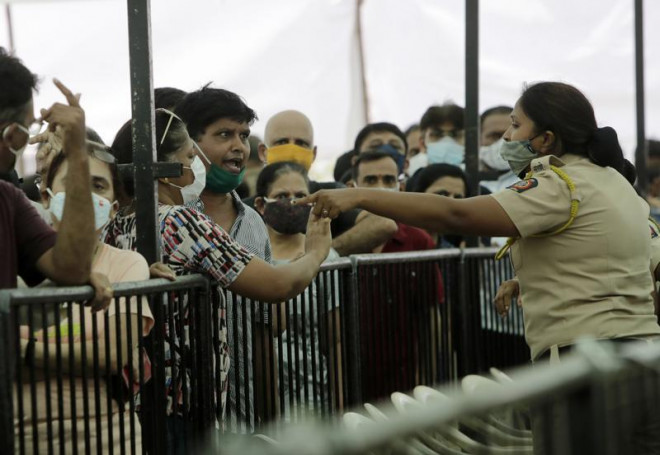 Một người đàn ông tranh cãi với cảnh sát bên ngoài một trung tâm tiêm phòng ở TP Mumbai - Ấn Độ hôm 28-4. Ảnh: AP
