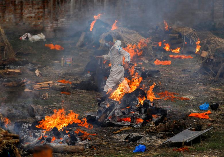 Một người đàn ông mặc trang phục bảo hộ y tế chạy qua giàn hỏa thiêu tại lò hỏa táng ở thủ đô Kathmandu của Nepal hôm 11/5. Ảnh: Reuters