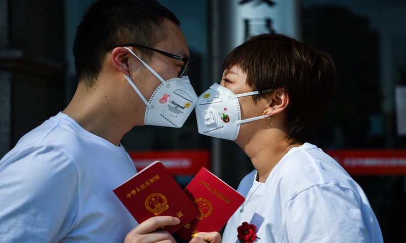 Cặp đôi đeo khẩu trang hôn nhau khi đi đăng ký kết hôn ngày Tình nhân Trung Quốc năm ngoái. Ảnh: VCG