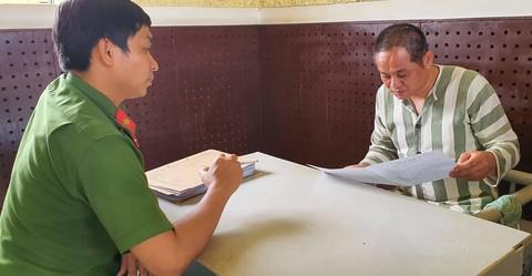 Bị can Đỗ Văn Minh đọc lại cẩn thận lời khai của mình sau buổi làm việc với ĐTV, có phóng viên chứng kiến. Ảnh: Ngọc Hà