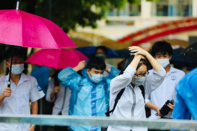 Thí sinh đội mưa đến điểm thi ở Hà Nội ngày 13/6. Ảnh: Như Ý