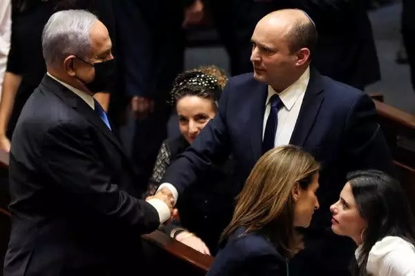 Ông Netanyahu bắt tay với tân Thủ
tướng Naftali Bennett sau khi thông qua chính phủ liên minh mới vào
ngày 13-6. Ảnh: Reuters