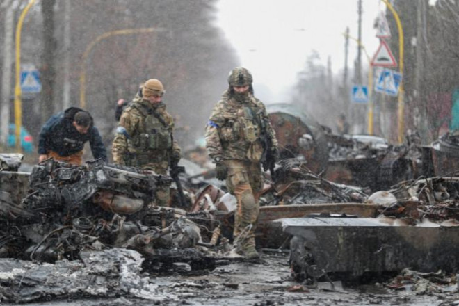 Binh sỹ Ukraine kiểm tra một phương tiện quân sự bị hư hại nặng vì giao tranh tại thành phố Bucha. Ảnh - EPA