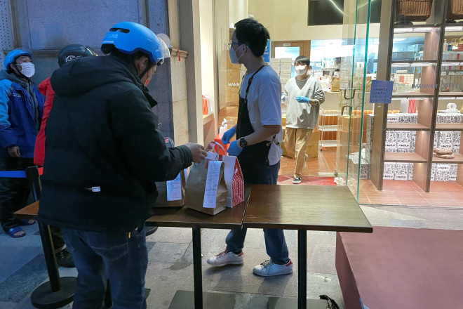 Nhân viên giao hàng chờ nhận đơn bên ngoài một cửa hàng ở TP Thượng Hải – Trung Quốc, hôm 20-4 Ảnh: REUTERS