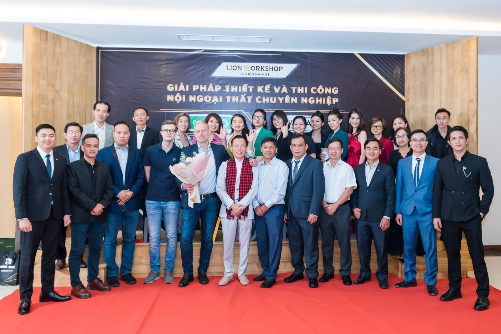 Các khách mời chụp hình cùng ban lãnh đạo Lion Workshop tại backdrop sự kiện được thiết kế bằng gỗ siêu bền Accoya
