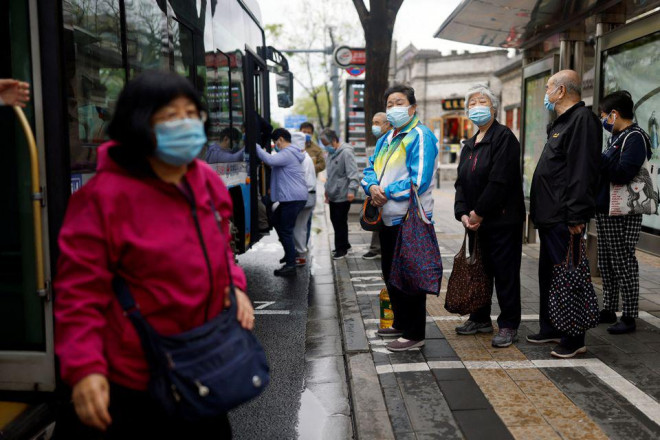 Hành khách đeo khẩu trang tại một trạm xe buýt ở Bắc Kinh ngày 28-4. Ảnh: Reuters