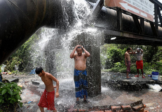 Người dân tắm gội dưới đường ống nước bị rò rỉ giữa tiết trời nóng bức ở Kolkata - Ấn Độ hôm 19-4 Ảnh: REUTERS