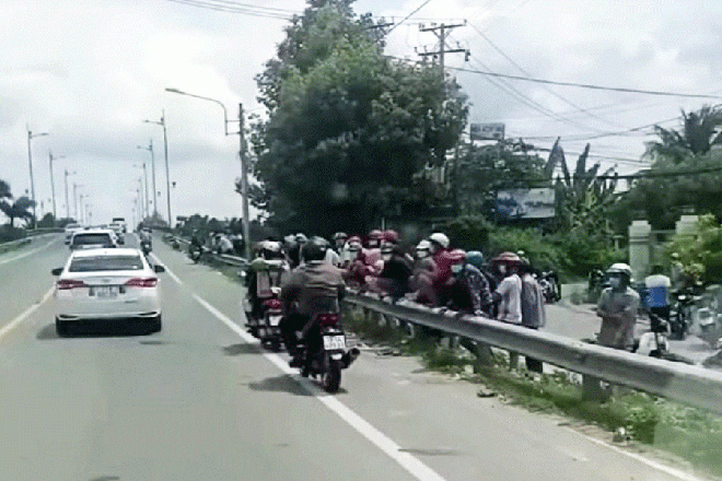 Người dân hiếu kỳ tập trung tại cầu Cái Cấm (xã Thanh Tân, huyện Mỏ Cày Bắc, tỉnh Bến Tre) theo dõi việc khám xét nơi ở của 1 đối tượng có liên quan