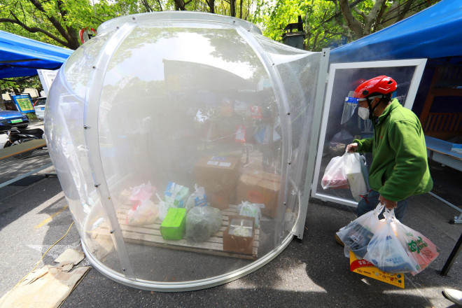 Một người giao hàng đặt đồ đạc vào buồng khử trùng ở Thượng Hải. Ảnh: REUTERS