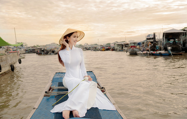 Hình ảnh Hoa hậu Phan Thị Mơ đẹp thanh thoát trong tà áo dài ngồi thuyền tham quan chợ nổi khiến nhiều người dân địa phương và du khách chú ý.
