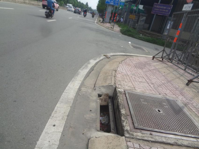 Rác đọng dưới hố sau khi bị mất nắp chắn rác, dễ gây ách tắc dòng chảy khi trời mưa. Ảnh chụp ngày 9-6.