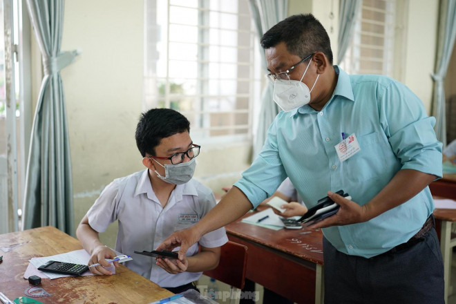 Một cán bộ coi thi đang tạm thu ốp lưng máy tính của một thí sinh.