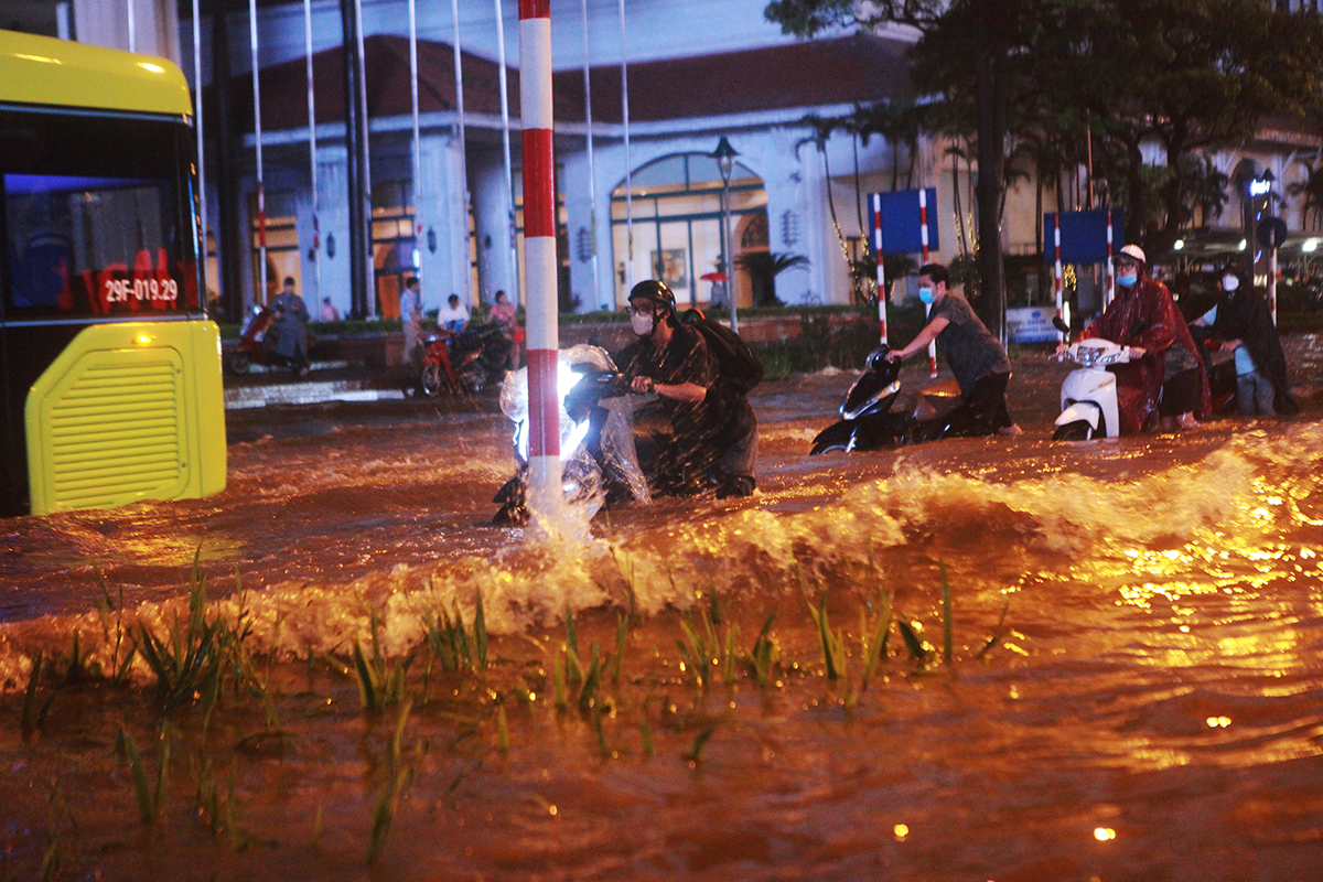 Nước ngập mênh mông, xe buýt đi tạo thành sóng lớn khiến người dân dắt xe máy kế bên chao đảo