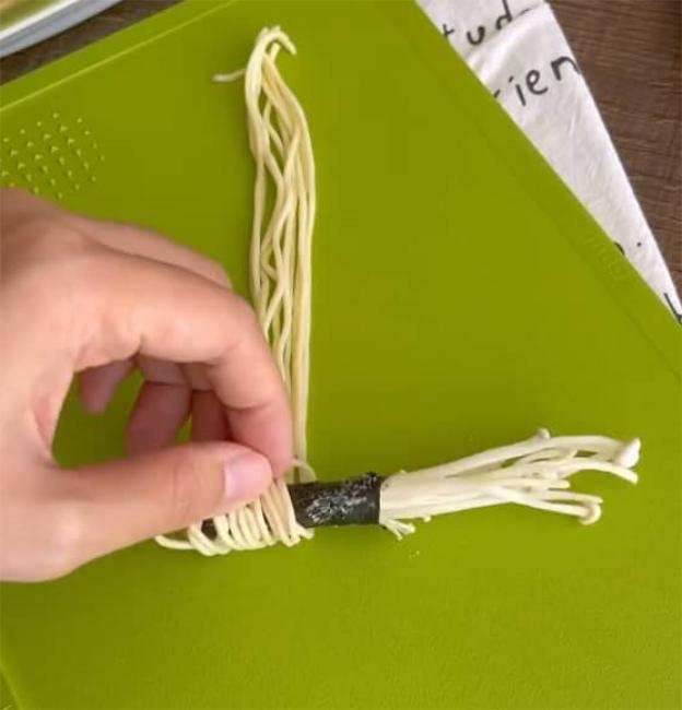Cuốn lá dong biển đã phết bột vào một nhúm nấm kim châm rồi cuốn mì tôm ra ngoài cùng, như hướng dẫn trong hình.
