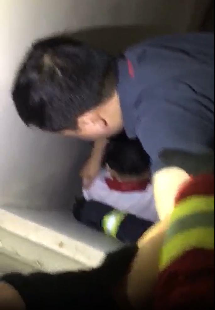 Lực lượng chức năng tiếp cận cháu bé mắc kẹt ở hố tum tầng 20 chung cư. Ảnh cắt từ clip