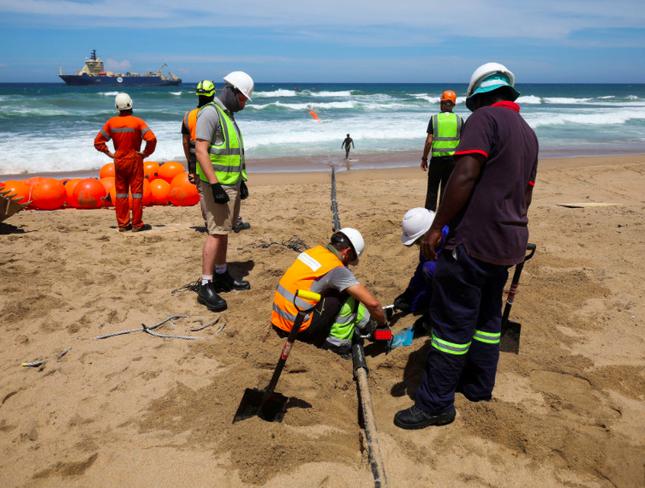 Lắp đặt cáp ngầm qua bãi biển Amanzimtoti của Nam Phi ngày 7/2. (Ảnh: Xinhua)