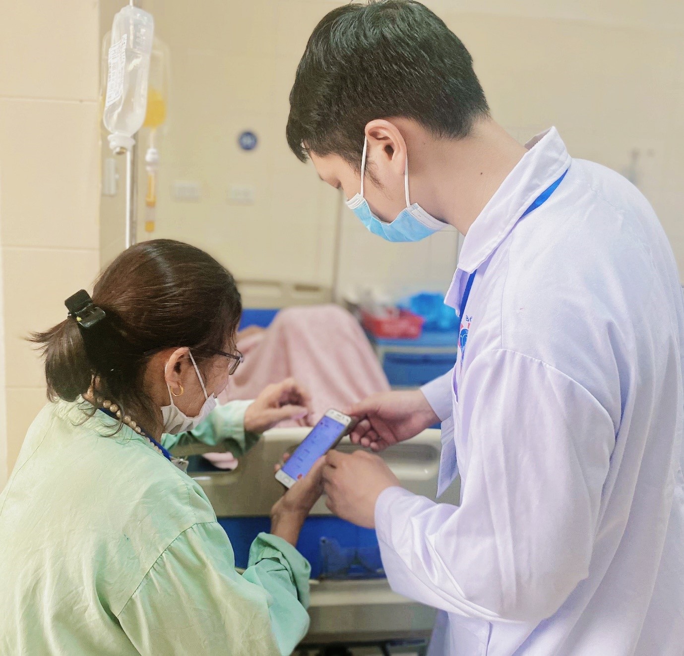 Điều phối viên chăm sóc hướng dẫn người nhà bệnh nhân sử dụng ứng dụng chăm sóc sức khỏe từ xa cho bệnh nhân ung thư dạ dày sau phẫu thuật