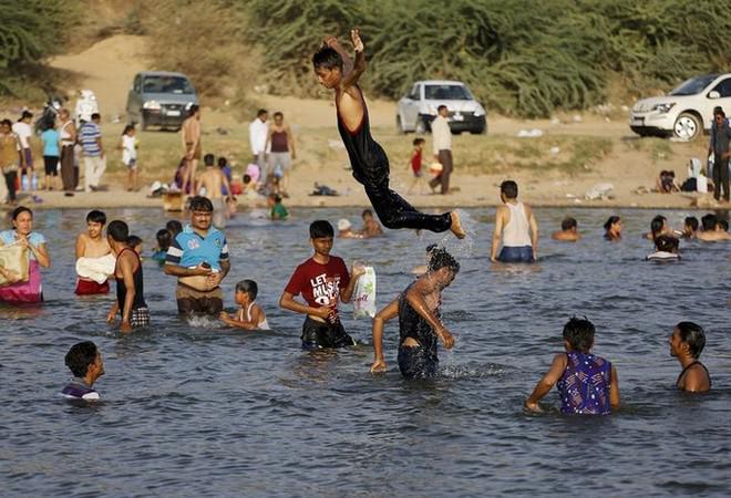 Người dân địa phương đổ ra sông tắm giải nhiệt ở ngoại ô thành phố Ahmedabad, Ấn Độ