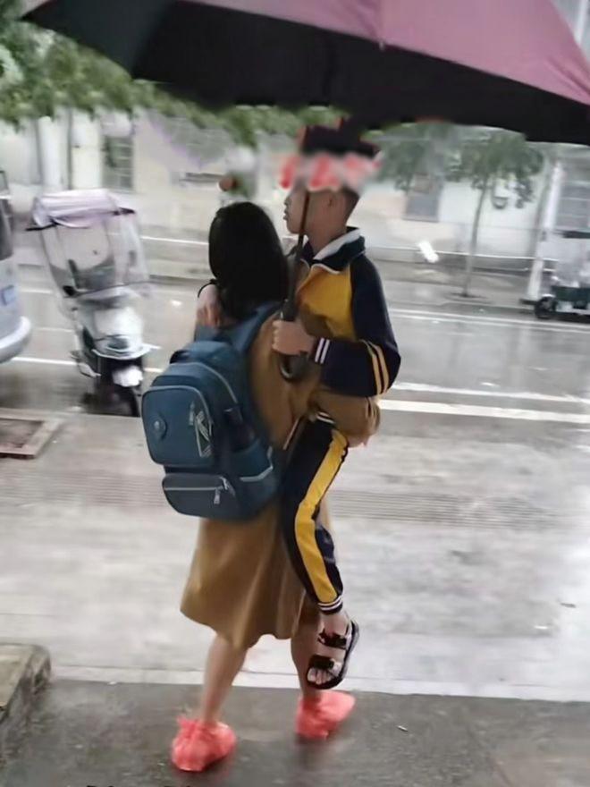 Một bà mẹ ở Trung Quốc đã bế con trai giữa trời mưa lất phất, chị còn cẩn thận che ô và mang cặp giúp con.
