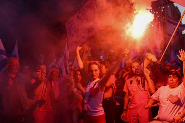 Người biểu tình Israel cầm loa và pháo sáng tại TP Tel Aviv. Ảnh: REUTERS