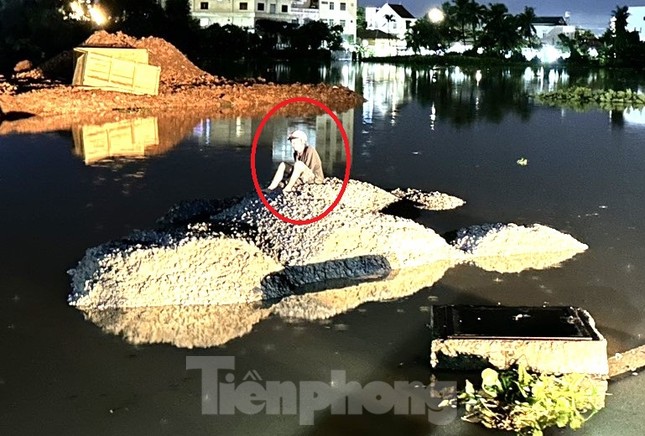 Người đàn ông bị nước cuốn trôi ngồi chờ lực lượng chức năng đến cứu