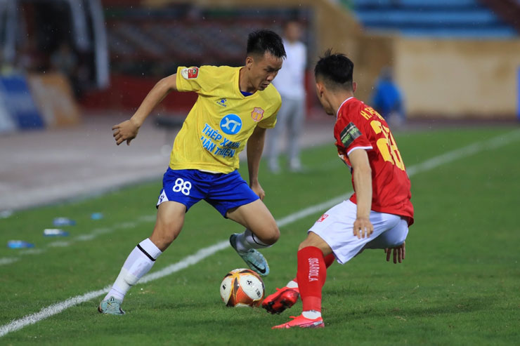 Tô Văn Vũ (áo vàng, Nam Định) đi bóng ở sát biên khi bị Hoàng Thái Bình (Thanh Hóa) theo sát