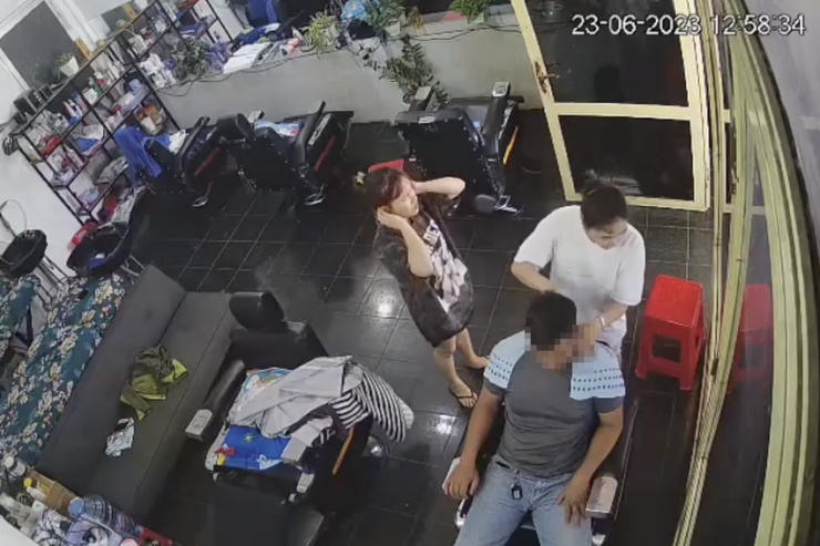 Ông V. đang được cắt tóc, sau đó đút "nhầm" điện thoại. Ảnh cắt từ clip