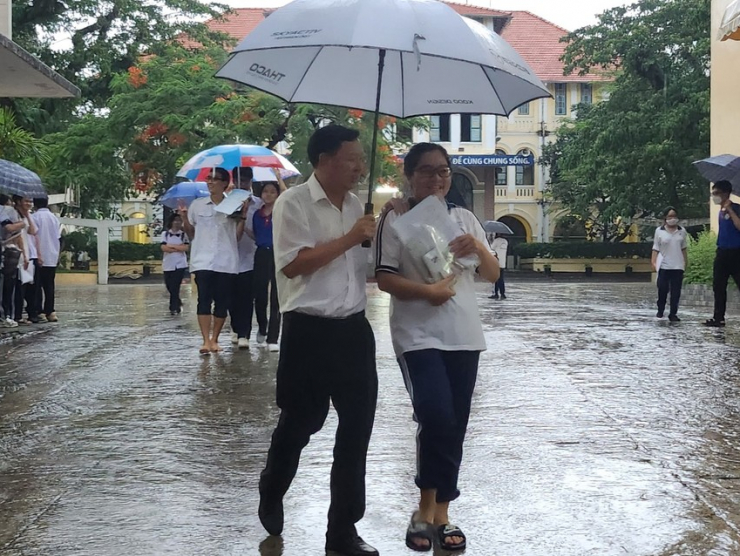 Thí sinh thi xong môn Toán ra về trong cơn mưa chiều. Ảnh: NGUYỄN QUYÊN