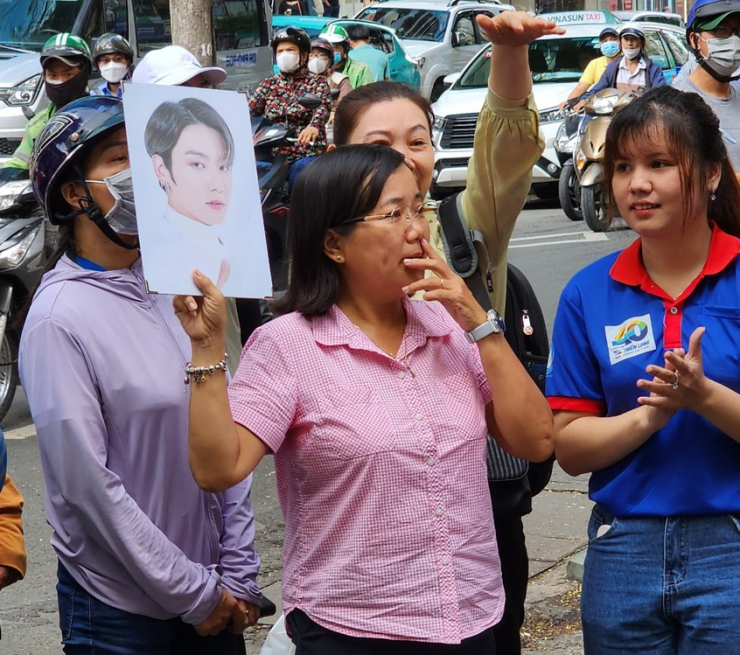 Cô Bùi Thị Kim Chi mang theo ảnh ca sĩ mà con yêu thích đứng chờ trước điểm thi Trường THPT chuyên Trần Đại Nghĩa, quận 1. Ảnh: NVCC