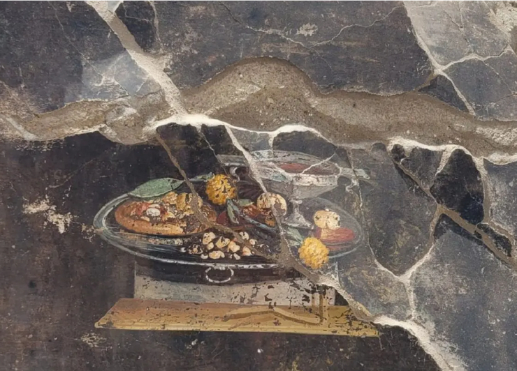 Một mâm thức ăn đãi khách được trình bày trên đĩa bạc sang trọng, với một số món thôn dã của người Hy Lạp - La Mã cổ đại, bao gồm... một cái bánh y hệt bánh pizza - Ảnh: CÔNG VIÊN KHẢO CỔ POMPEII