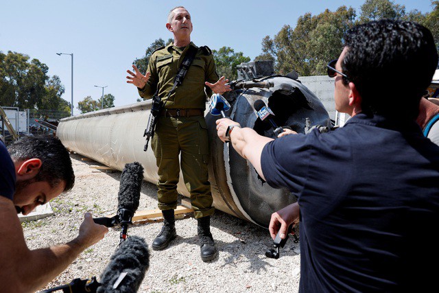 Người phát ngôn quân đội Israel Daniel Hagari nói chuyện với giới truyền thông hôm 16-4 tại căn cứ quân sự Julis, miền Nam Israel, bên cạnh vật thể mà Israel cho biết là một phần tên lửa đạn đạo của Iran rơi xuống biển Chết trong cuộc tấn công ngày 13 và 14-4 vừa qua - Ảnh: REUTERS