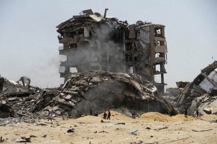 Người dân đi ngang đống đổ nát của các tòa nhà ở miền bắc Gaza hôm 22-4. Ảnh: REUTERS