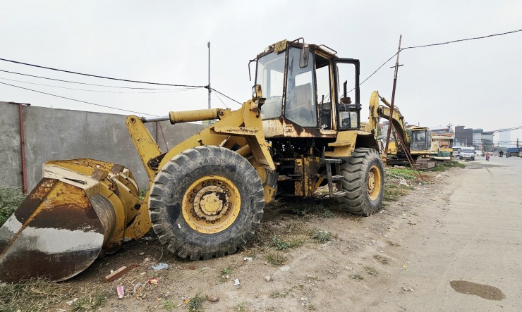 Máy móc thiết bị phục vụ thi công dự án đường Vành đai 2,5 xếp hàng dài bên đường và khu vực văn phòng điều hành.