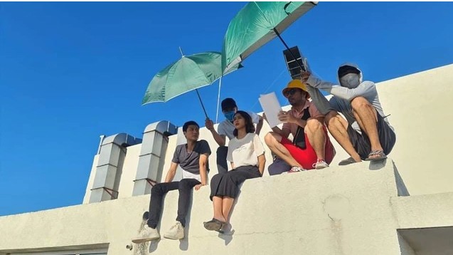 Các diễn viên và thành
viên ê-kíp đoàn phim dùng ô che, đội mũ, mặc áo chống nắng, đeo
khẩu trang khi ghi hình.