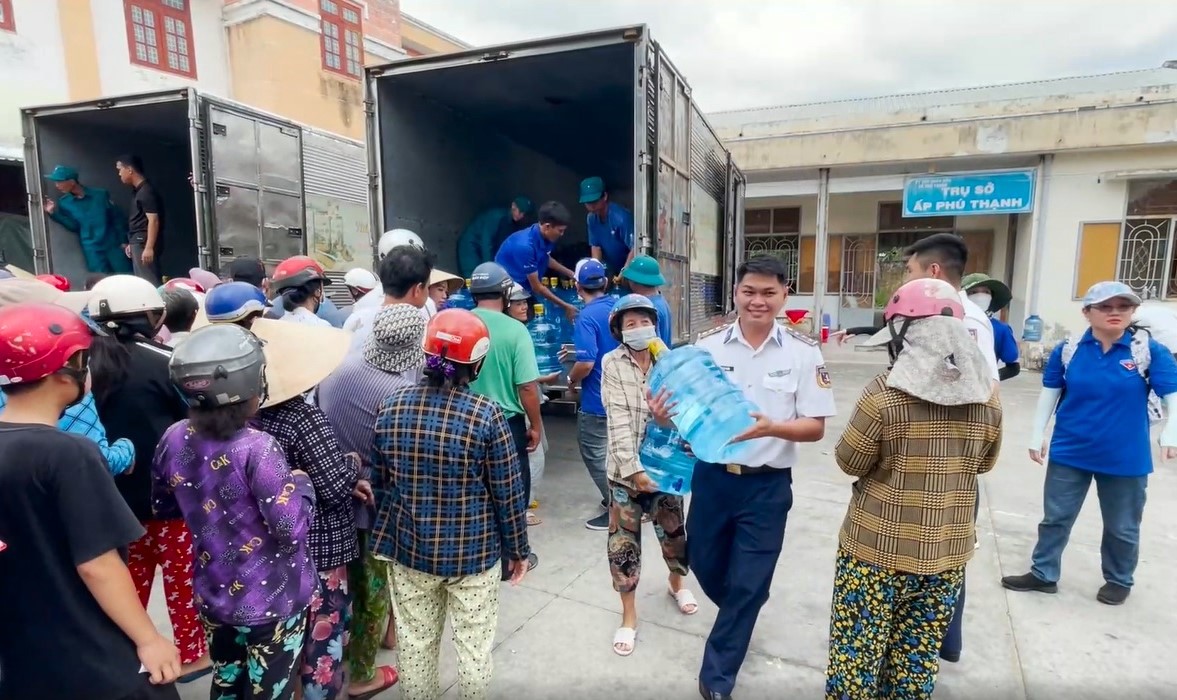 Cảnh sát biển giúp dân vận chuyển nước uống ra xe.