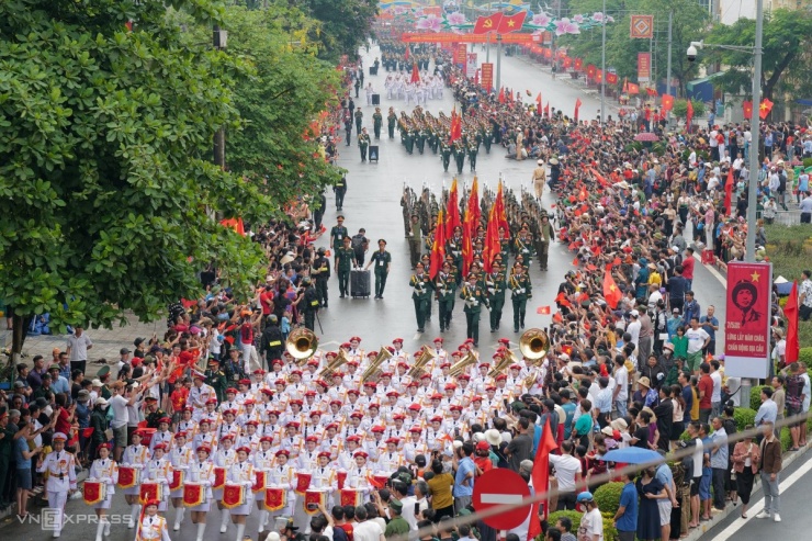 Từ 6h30 sáng 7/5, Điện Biên Phủ mưa lớn, hàng nghìn người vẫn đội mưa, đứng chật kín các ngả đường Hoàng Văn Thái, Võ Nguyên Giáp... để xem các đoàn diễu binh, diễu hành đi qua.