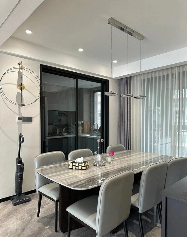 Bàn ăn bằng đá cẩm thạch hình bầu dục được kết hợp với những chiếc ghế ăn màu xám.

