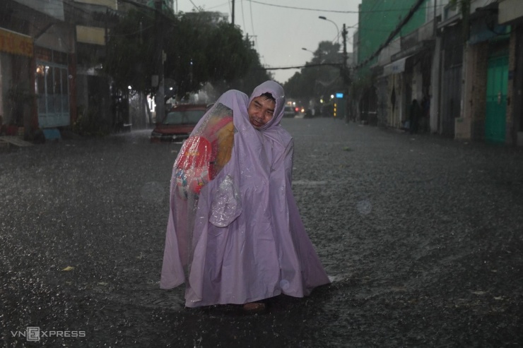 Ông Phan Văn Tự ẵm con đi học về nhà. "Mưa thì mát mẻ nhưng ngập quá cũng khổ", ông nói.