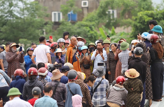 Nhiều người dân đứng xung quanh ông Tú dùng điện thoại quay video tại một bãi đất trống ở xã Cẩm Thịnh, huyện Cẩm Xuyên, trưa 17/5. Ảnh: Đức Hùng