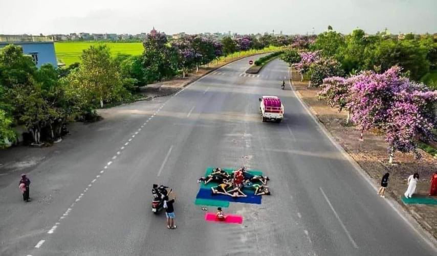 Nhóm người nằm, ngồi trên đường bộ để tập yoga, chụp ảnh.