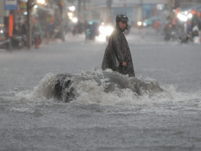 Nước từ cống trào lên đường trong mưa lớn ở TP HCM