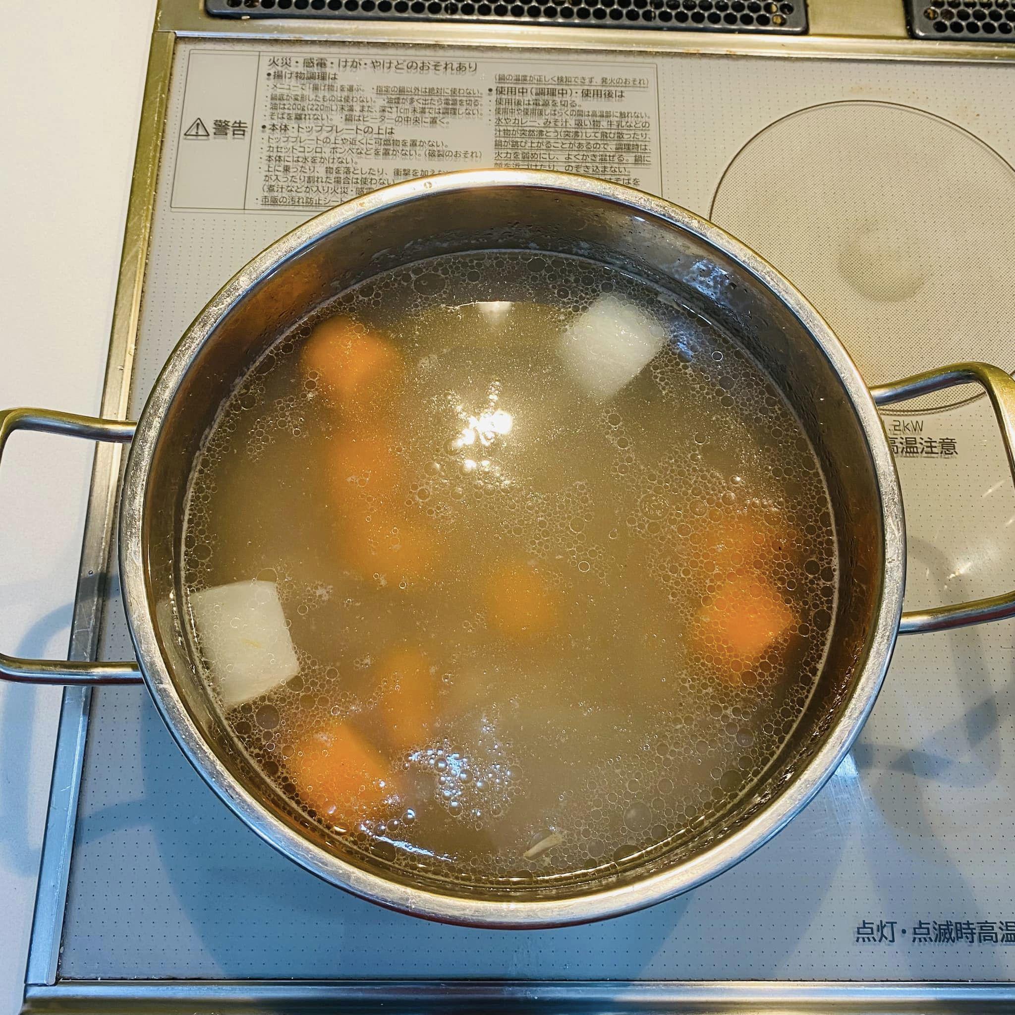 Nấu nước lèo: Đổ nước ngập xương ống, cà rốt, củ cải trắng và thêm gia vị.&nbsp;Hầm khoảng 60-70 phút.