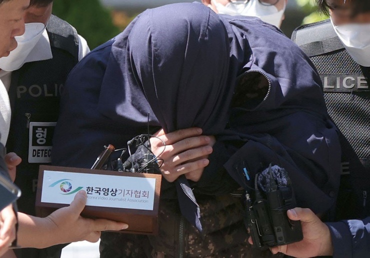 Một nghi phạm trong vụ sát hại một công dân Hàn Quốc ở Thái Lan che mặt khi bị cảnh sát Hàn Quốc áp giải để thẩm vấn tại TP Changwon (Hàn Quốc) ngày 15-5. Ảnh: YONHAP