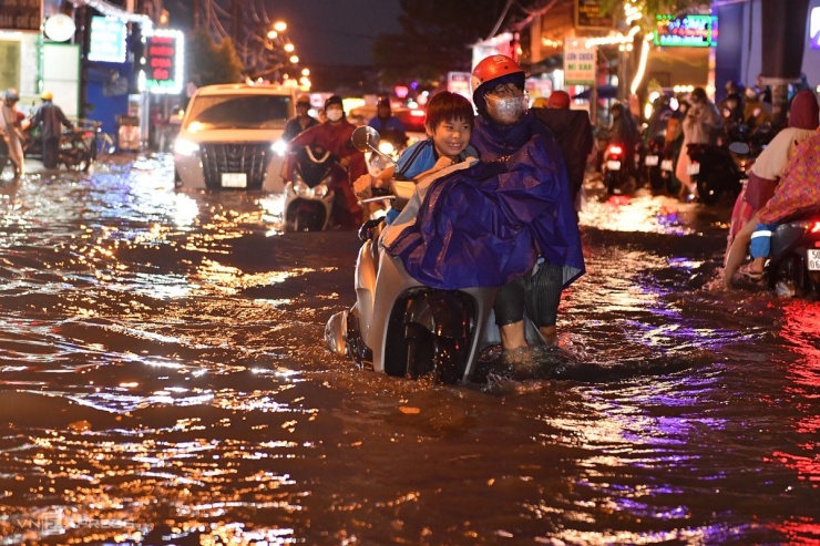 Nước ngập tới đầu gối, phụ huynh phải cho con ngồi trên yên xe, dắt xe chết máy về nhà.