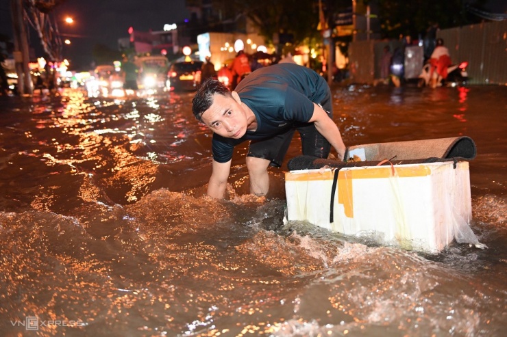 Để nước rút nhanh, nam thanh niên lấy rác, thông cống thoát nước trên đường Nguyễn Duy Trinh.