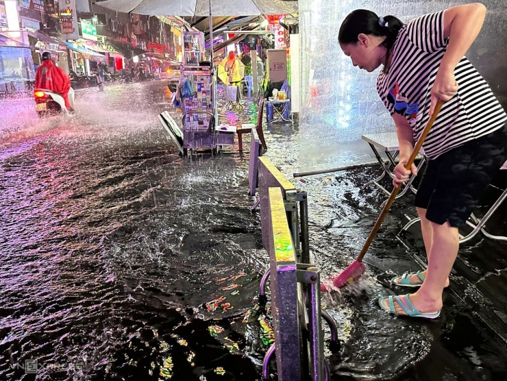 Người dân trên phố Bùi Viện dùng chổi đẩy nước trong quán ra ngoài.