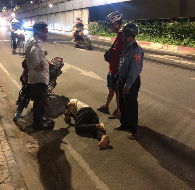 Nhiều người đi đường dừng lại hỗ trợ người đàn ông say xỉn ngủ trên đường